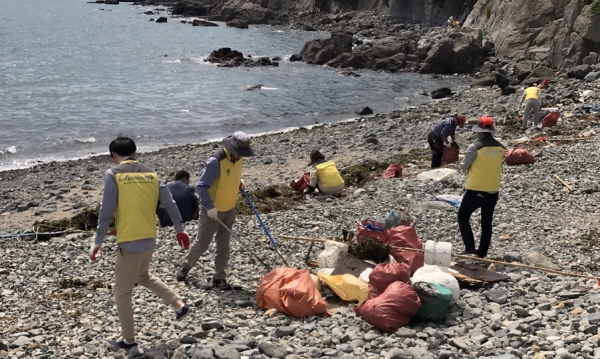 지난 23일 여수시 만덕동 주민센터 공무원들이 만성리 해변에 몰려온 해양쓰레기를 수거하고 있다.