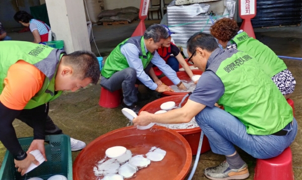 지난 4일 ‘사랑해 빨간밥차’ 봉사에 동참한 여수시 화양면 주민자치위원들이 화동농협 앞에서 설거지를 하고 있다.