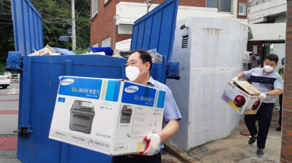 지난 9일 류갑선 미평동장(왼쪽) 등이 강박적 수집벽으로 집안에 쓰레기를 쌓아 놓고 있던 어르신의 집에서 쓰레기를 가지고 나오고 있다.