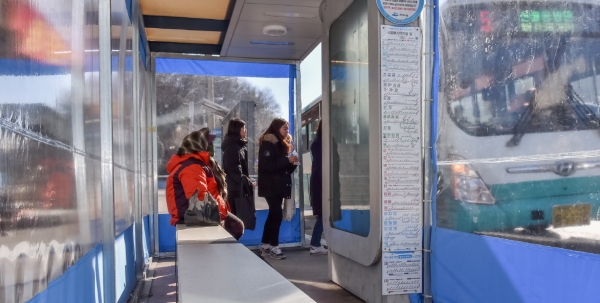 여수시민들이 발열의자와 온실텐트가 설치된 버스정류장에서 추위를 피하고 있다.