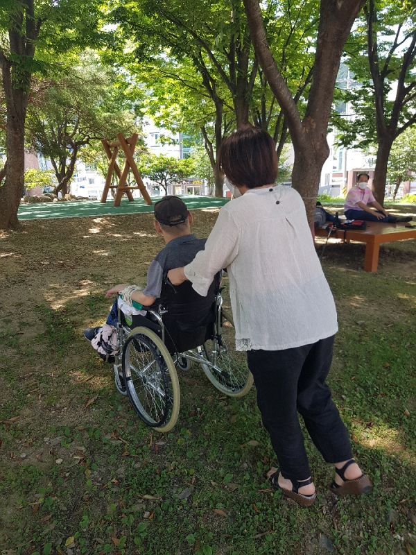 ▲ 장애인활동지원사가 거동이 불편한 장애인과 함께 산책을 하고 있다.